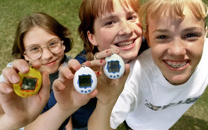 Drei Freundinnen halten stolz ihre Tamagotchis in die Kamera, 1997